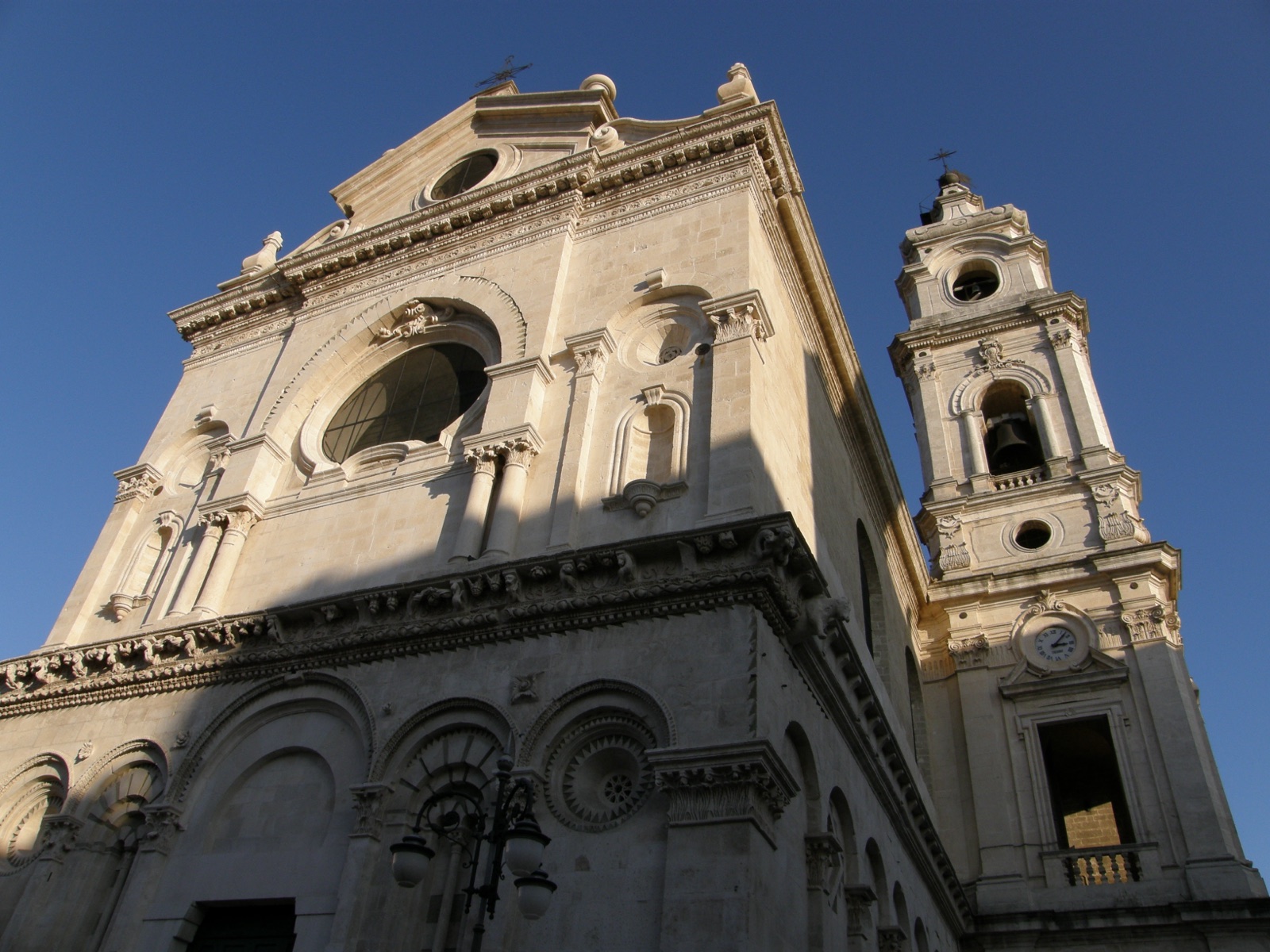 La facciata e il campanile barocco della Cattedrale di Foggia visti dal basso, in pietra chiara.